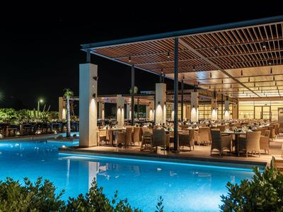 Modern restaurant next to a lit outdoor pool at night.