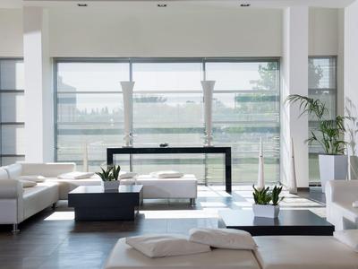 Modern bright living room with large windows and white furniture.