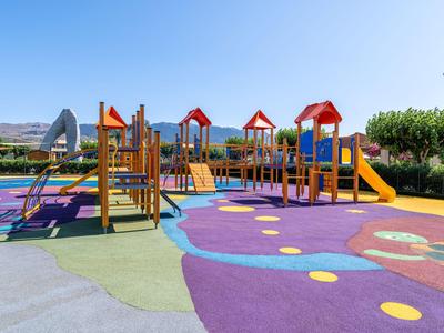 Bunter Spielplatz mit Rutschen und Klettergeräten unter klarem Himmel in einem Hotelbereich.