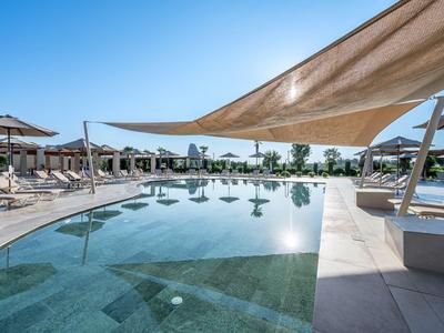 Moderner Hotelpool mit Sonnensegeln und Liegestühlen an sonnigem Tag.