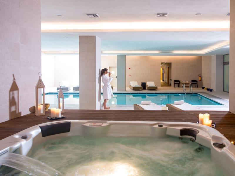 Blick auf einen Whirlpool mit Wasser und Kerzen vor einem hellen Innenpoolbereich im Hotel.