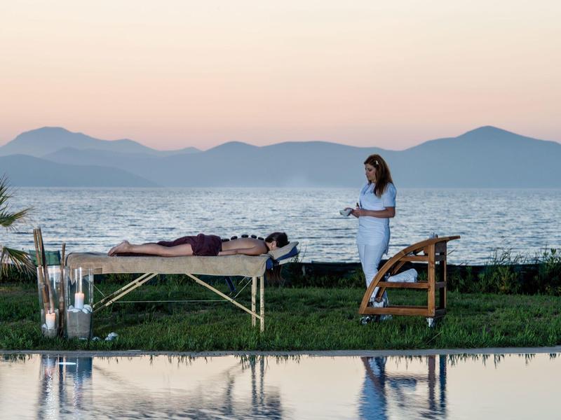 Frau bereitet draußen eine Massagebank am Meer bei Sonnenuntergang vor.