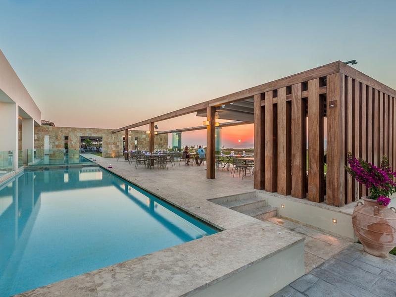 Moderner Außenpoolbereich mit Lounge und Holzstruktur bei Sonnenuntergang