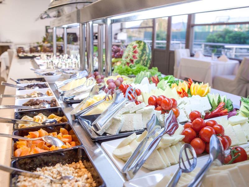 Buffet mit frischem Gemüse, Salaten und verschiedenen Speisen in einem hellen Restaurant.