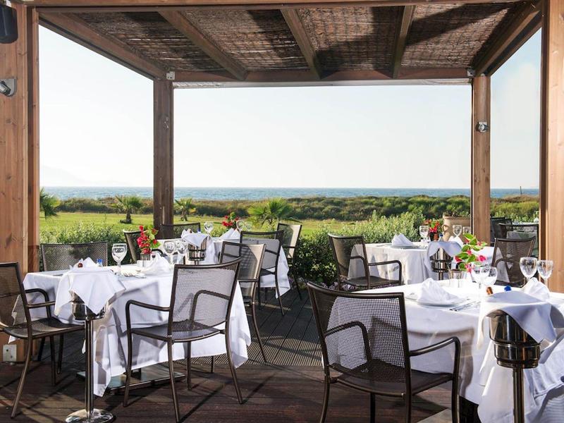 Terrassenrestaurant mit gedeckten Tischen, weißen Tischdecken und Blick auf grüne Landschaft.