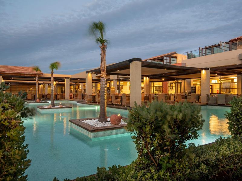 Moderner Hotelpool mit Palmen und Sitzbereichen bei Dämmerung.