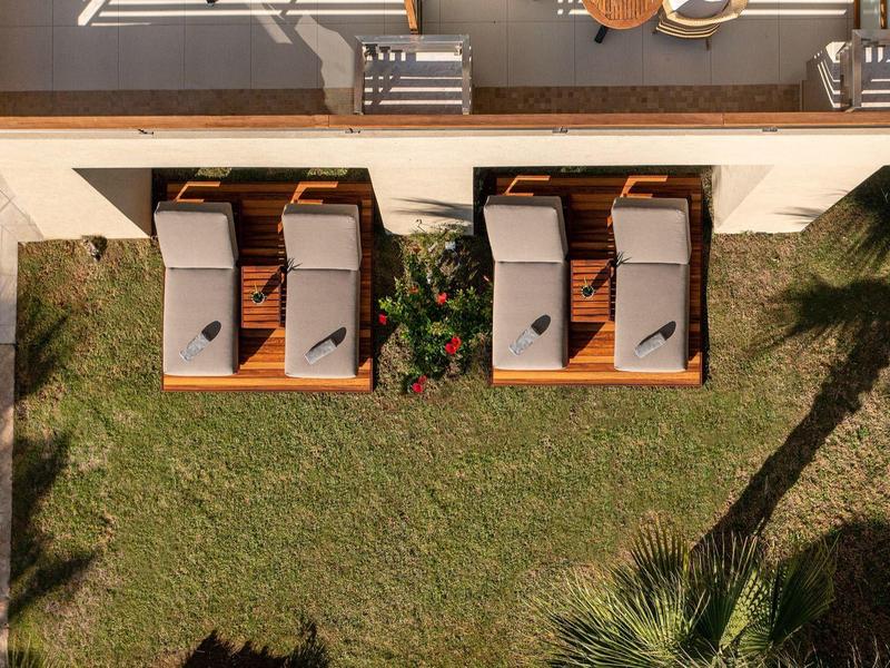 Vogelperspektive auf zwei Liegestühle auf Gras neben einem Pool und einer Terrasse.