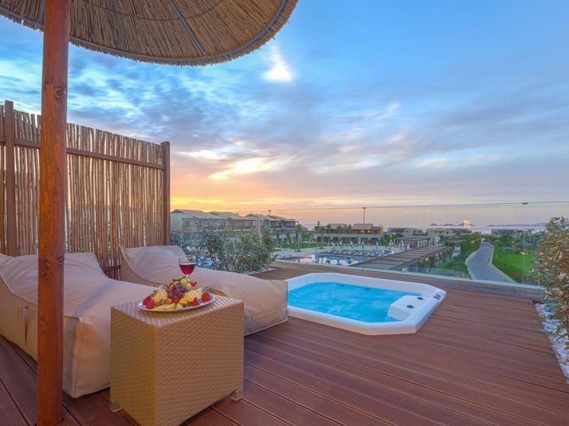 Terrasse mit Lounge-Sofa und kleinem Pool mit Blick auf Landschaft und Sonnenuntergang.
