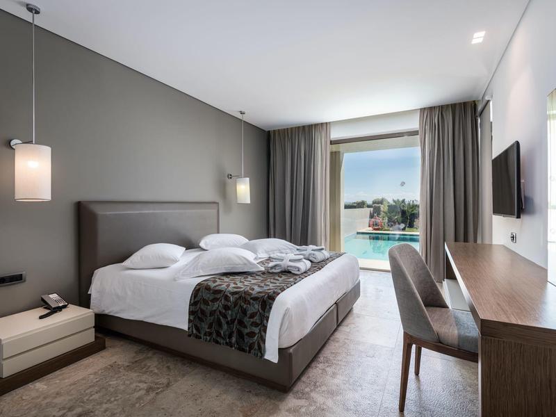 Modernes Hotelzimmer mit zwei Einzelbetten, Schreibtisch, Fernseher und Blick auf den Pool.