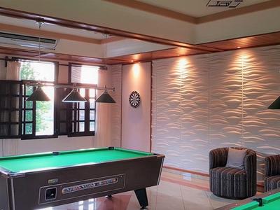 Interno con tavoli da biliardo, poltrone e grandi finestre in una stanza illuminata con calore