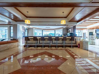 Hall d'entrée d'hôtel moderne avec comptoir de réception, chaises et grande fenêtre donnant sur l'extérieur.