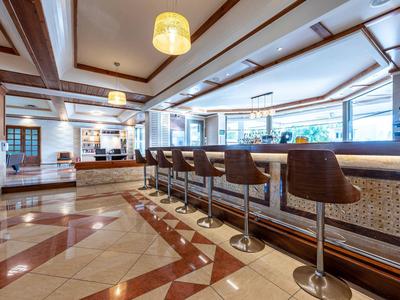 Espace de bar moderne d'hôtel avec comptoir, tabourets et sols en marbre clair.