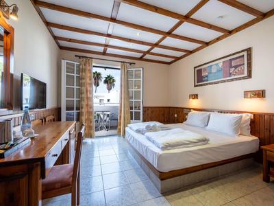 Chambre d'hôtel lumineuse avec lit double, mobilier en bois et balcon avec vue sur la mer.