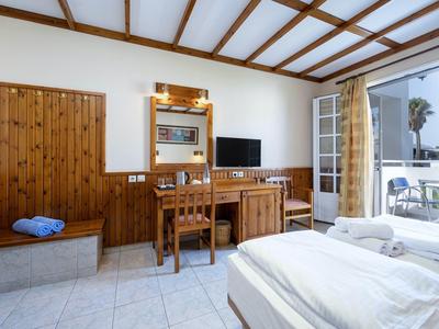 Chambre d'hôtel lumineuse avec meubles en bois, TV, balcon et vue sur la mer