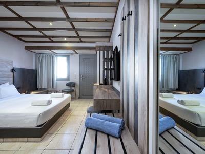 Chambre d'hôtel moderne avec lit double, bureau et grand miroir sur le mur.