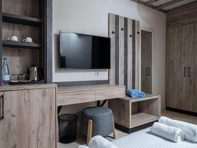 Chambre d'hôtel moderne avec armoire en bois, télévision et tabourets.