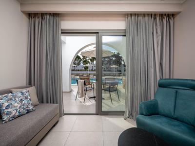 Vue d'une pièce avec canapé et fauteuil vers une terrasse avec table et chaises.