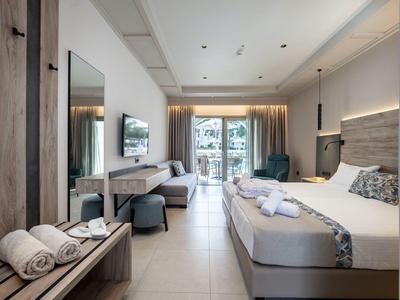 Chambre d'hôtel lumineuse avec grand lit, bureau, TV et balcon avec vue extérieure.