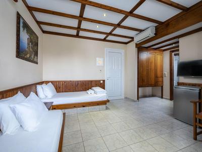 Une chambre d'hôtel lumineuse avec deux lits simples, des meubles en bois et une télévision murale.