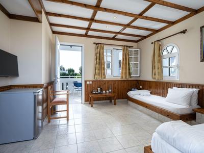 Chambre d'hôtel lumineuse avec sol carrelé, meubles en bois et balcon donnant sur la verdure.