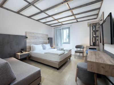 Nowoczesny pokój hotelowy z łóżkiem podwójnym, sofą, biurkiem i telewizorem na ścianie.