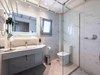 Nowoczesna łazienka z szklaną prysznicem, podświetlanym lustrem i toaletą.