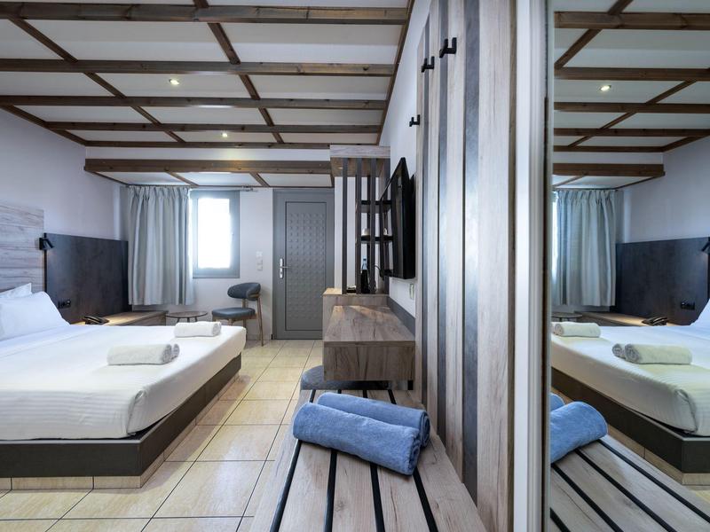 Chambre d'hôtel moderne avec lit double, bureau et grand miroir sur le mur.