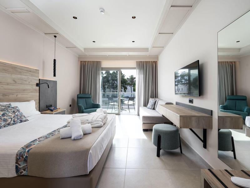 Chambre d'hôtel moderne avec lit double, balcon et décoration minimaliste en pleine lumière du jour.