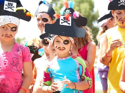 Bambini vestiti da pirati con cappelli e trucco durante un evento all'aperto soleggiato.