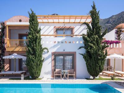 Moderner weißer Ferienbungalow mit Pool und zwei hohen Bäumen an der Fassade.