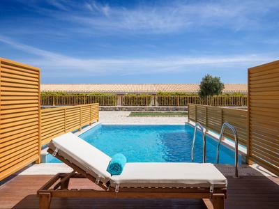 Area piscina privata con lettino e asciugamano blu, vista su paesaggio aperto sotto cielo azzurro.