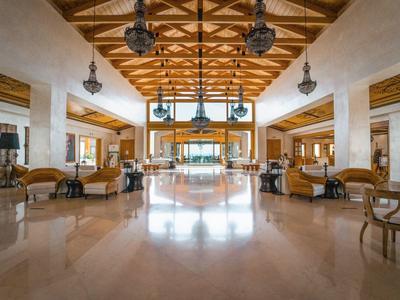 Ampia hall dell'hotel con soffitto in legno, pavimenti lucidati e aree salotto eleganti.