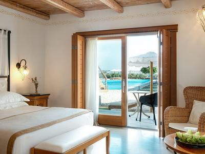 Camera d'hotel luminosa con letto matrimoniale e vista sulla terrazza con piscina e mare.