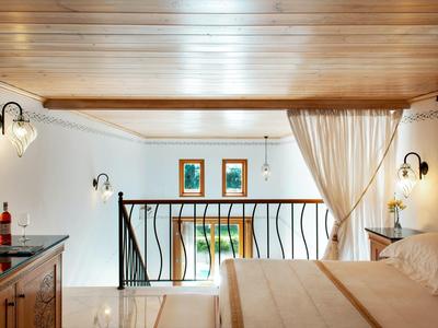 Camera mansardata accogliente in legno con illuminazione soffusa, piccolo balcone e quadri incorniciati.