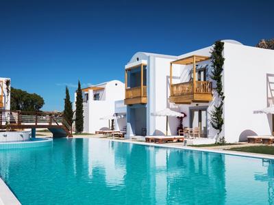 Complesso alberghiero moderno con edifici imbiancati a calce e grande piscina sotto un cielo azzurro.