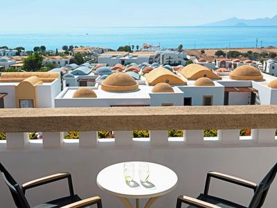 Balcone con sedie e tavolo con vista su una località con tetti a cupola e il mare sullo sfondo.