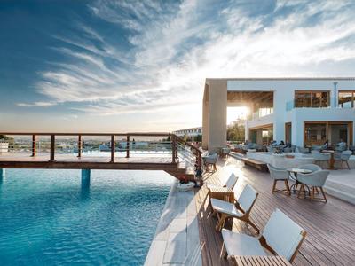 Terrazza moderna dell'hotel con piscina, sedie a sdraio e cielo al tramonto.