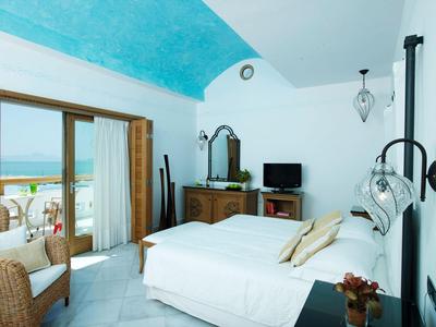 Chambre lumineuse avec lit double et balcon offrant une vue sur la mer.