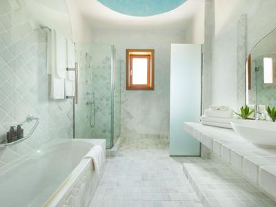 Salle de bain moderne et lumineuse avec baignoire, douche, doubles lavabos et fenêtre en bois.