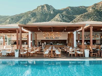 Restaurant d'hôtel ouvert avec piscine et montagne en arrière-plan.