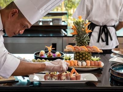 Chef décore soigneusement de petits plats artistiques sur des plateaux dans une cuisine professionnelle.