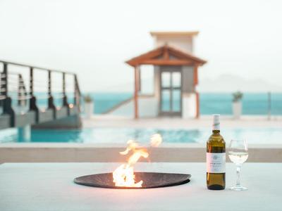 Vin et verre à côté d'un foyer près de la piscine avec vue sur la mer