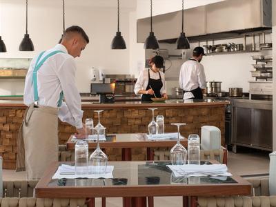 Un serveur prépare les tables avec des verres et des couverts dans un restaurant moderne.