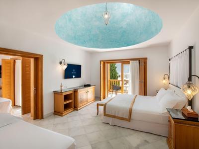 Chambre d'hôtel lumineuse avec deux lits, meubles en bois et une alcôve de plafond bleue ronde.