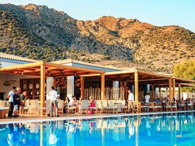 Hôtel avec piscine extérieure devant un paysage montagneux au coucher du soleil.