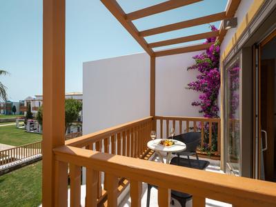 Balcon avec rambarde en bois, petite table et chaises, décoration florale et vue sur le jardin.
