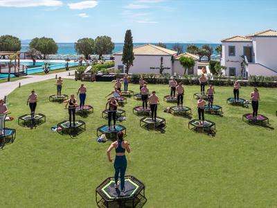 Entraînement de groupe sur des trampolines sur une pelouse verte avec vue sur la mer par ciel clair.