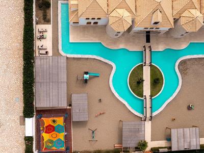 Vue aérienne d'une piscine d'hôtel avec des pavillons et des espaces de repos.