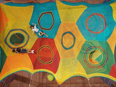 Hamac coloré avec des motifs géométriques et deux personnes allongées dessus dans un cadre détendu.