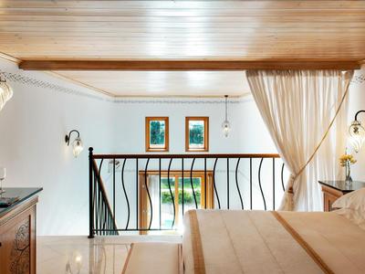 Elegantes Schlafzimmer mit Balkon, Holzbalkendecke und moderner Beleuchtung